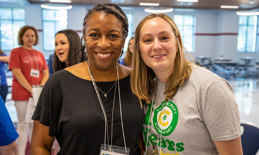 Two administrators stand together and smile